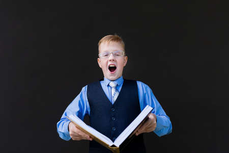 the schoolboy with a book on a black backgroundの写真素材