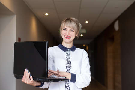 Beautiful and happy blonde in the hands of a laptop