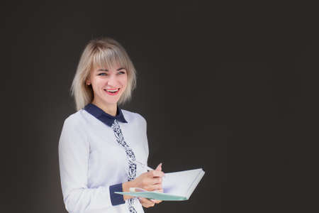 Happy blonde, teacher against the background of the black wall