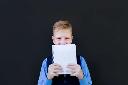 the Schoolboy looks out from under the notebook