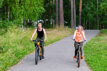 the man and woman ride bikes through the woods