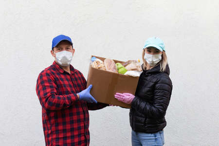 the volunteers in protective masks with a box of food