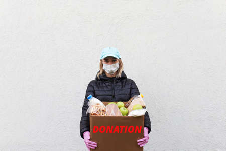 the Girl volunteer in protective mask with food box, donationの写真素材