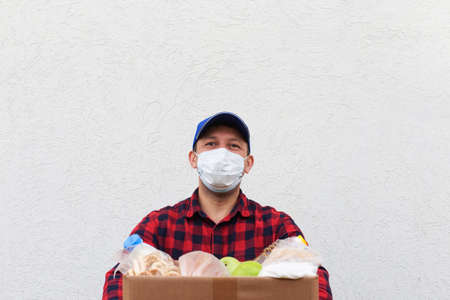 the volunteer in a protective mask with a box of food, donationの写真素材