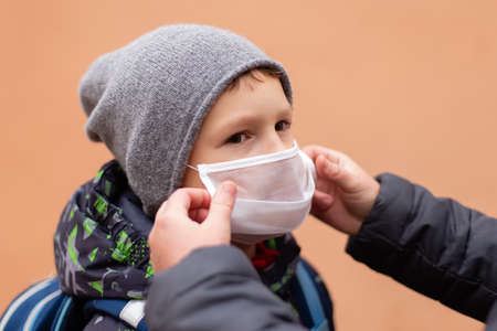the Mom adjusts the mask to the child on the streetの写真素材