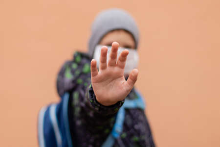 A schoolboy in a protective mask shows his hand STOP