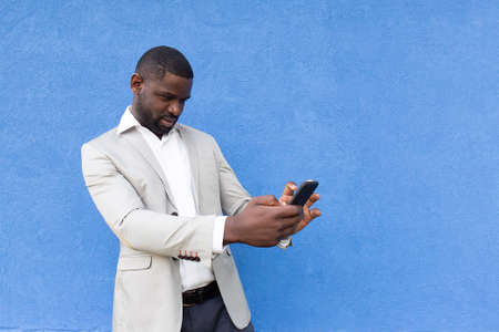 the happy African American with phone on blue backgroundの写真素材