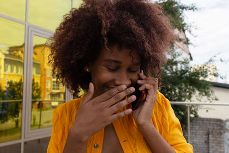 beautiful and happy African American on the street with her phone