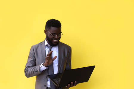 an Image of happy excited young african man isolated over yellow background using laptop computer.の写真素材