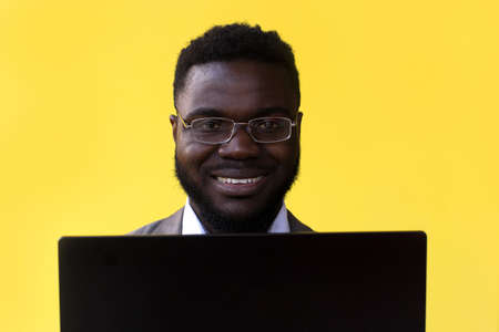 an Image of happy excited young african man isolated over yellow background using laptop computer.の写真素材