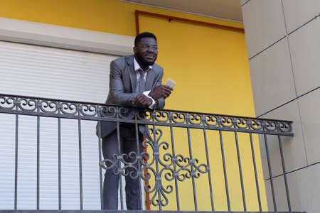 the African American drinks coffee and talks on the phone, on a yellow backgroundの写真素材