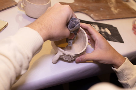 man handles a clay bowl, in the workshop
