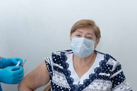 male nurse gives an injection to an elderly woman, a vaccinationの写真素材