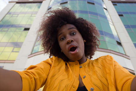 Happy and young African American woman takes a selfie, close-up