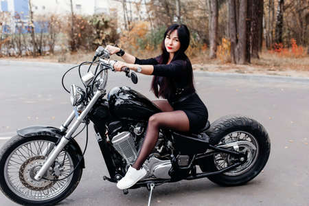 the beautiful brunette in a dress on a motorcycle in the parkの写真素材