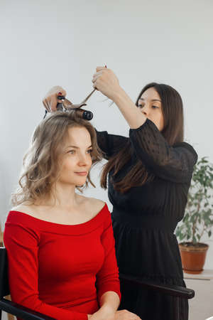 the master makes a hairstyle for a girl, beautiful curlsの写真素材