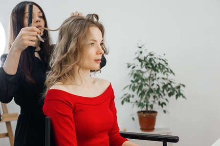 the master makes a hairstyle for a girl, beautiful curlsの写真素材