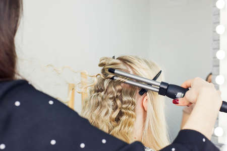 the master makes a hairstyle for a girl, beautiful curlsの写真素材