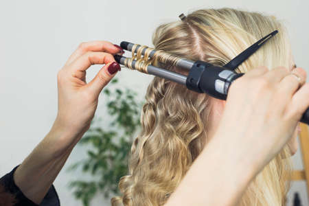 the master makes a hairstyle for a girl, beautiful curlsの写真素材