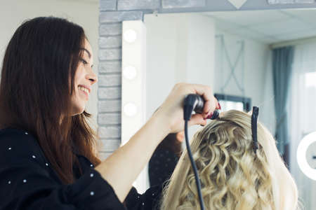 the master makes a hairstyle for a girl, beautiful curlsの写真素材