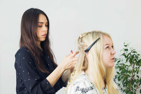 the master makes a hairstyle for a girl, beautiful curls