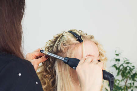 the master makes a hairstyle for a girl, beautiful curlsの写真素材