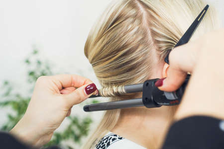 the master makes a hairstyle for a girl, beautiful curlsの写真素材