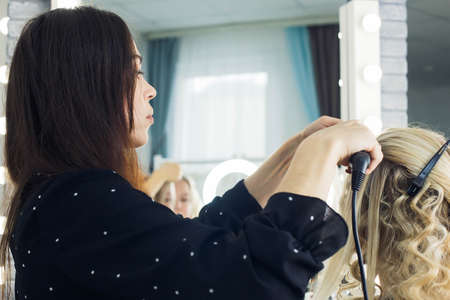 the master makes a hairstyle for a girl, beautiful curlsの写真素材