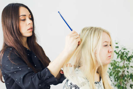 the master makes a hairstyle for a girl, beautiful curlsの写真素材