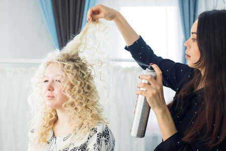 the master makes a hairstyle for a girl, beautiful curlsの写真素材