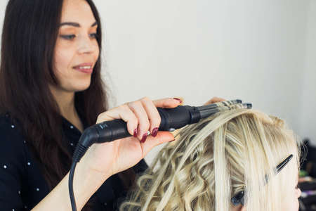 the master makes a hairstyle for a girl, beautiful curlsの写真素材