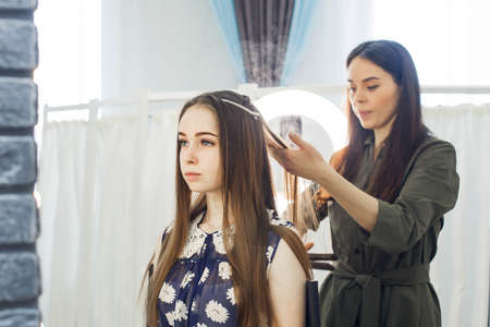 the master makes a hairstyle for a girl, beautiful curls