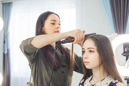 the master makes a hairstyle for a girl, beautiful curlsの写真素材
