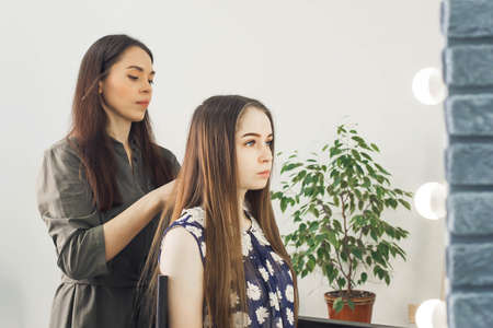 the master makes a hairstyle for a girl, beautiful curlsの写真素材