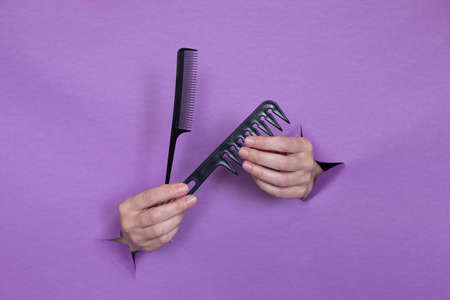 professional hair combs in the hands, on a purple background, holes in the background. Space for text.の写真素材
