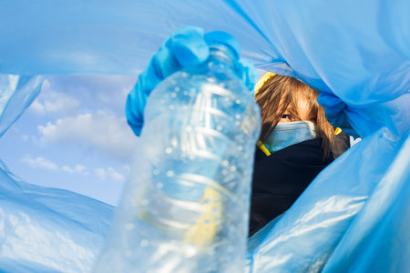 a woman throws a plastic bottle into a bag under the garbage, close-up, the concept of ecology and...