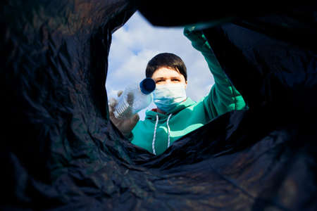 a woman throws a plastic bottle into a bag under the garbage, close-up, the concept of ecology and...