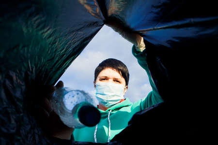 a woman throws a plastic bottle into a bag under the garbage, close-up, the concept of ecology and...