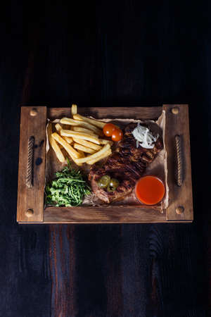 fillet steak with french fries on a wooden tray, beautiful serving, dark background.の写真素材