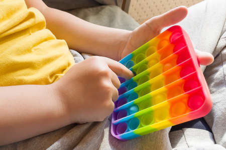 colorful anti-stress sensory fidget push pop it toy in children's hands.の写真素材