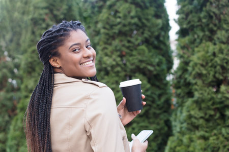happy african american woman on the street with coffee.の写真素材