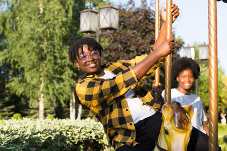 two happy African-American women in a park on an amusement ride in the summer.