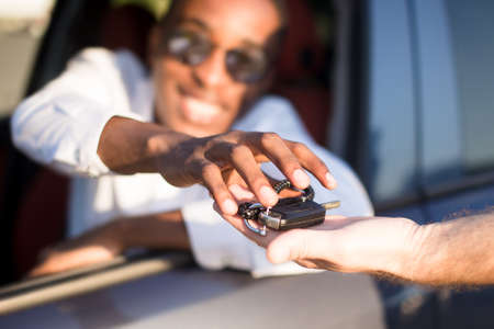 happy African American in a car with a key, in the summer.の写真素材
