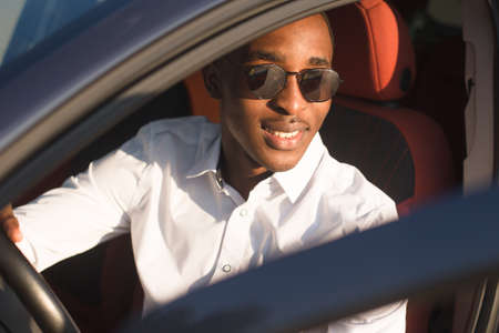 happy african american driving a car, in the summer.