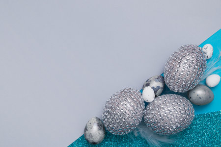 Easter creative background of a combination of paper, glitter and eggs in blue-green colors.の写真素材