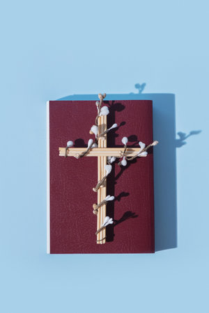 Cross decorated flowers with Holy Bible on blue background. Easter holiday minimalistic concept.
