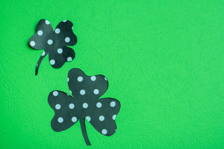 St. Patrick's Day minimalistic concept. Paper clover leaves on colored background with copy space.