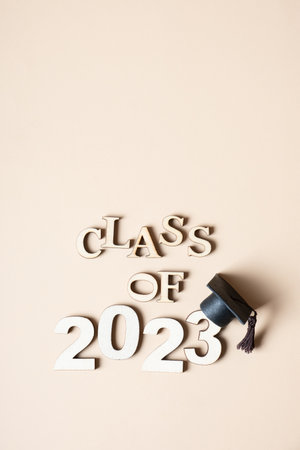 Class of 2023 concept. Wooden number 2023 with graduated cap on beige background