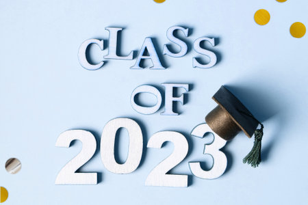 Class of 2023 concept. Wooden number 2023 with graduated cap on blue background with tinsel top view.の写真素材