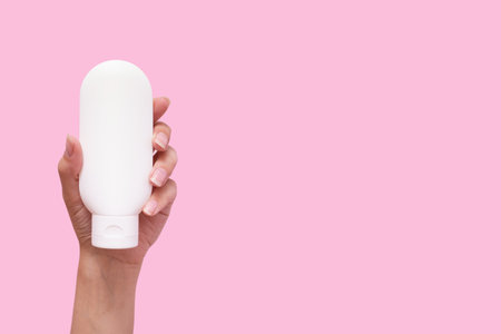 Female hand with cosmetic product in white container mock up on pink color background.の写真素材